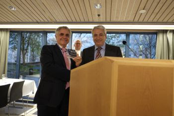 Two men in suits presenting an award at a conference lectern