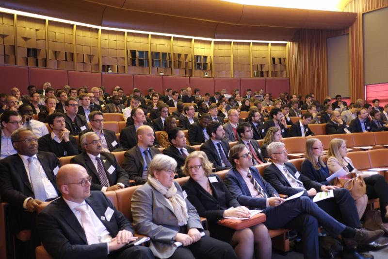 Audience of business attendees seated in a wood-paneled auditorium at the Energy Access Investment Forum