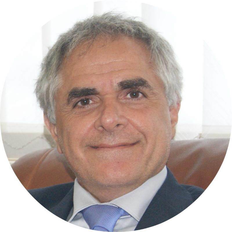Headshot of a smiling man with gray hair in a dark suit and light blue tie